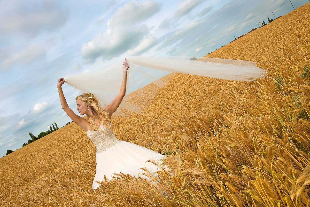 La mariée dans un champ avec son voile en l'air